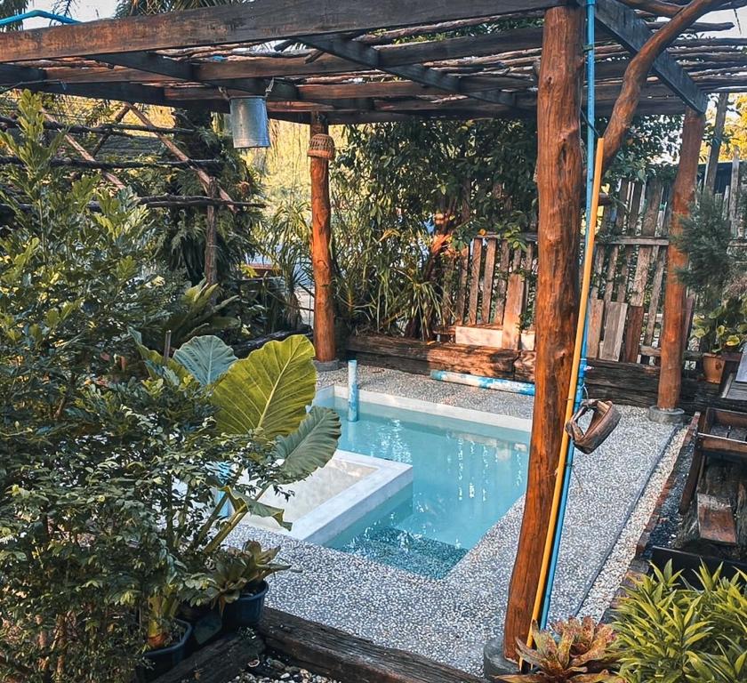 a pool with a wooden pergola and a swimming pool at Amarit Onsen Homestay 