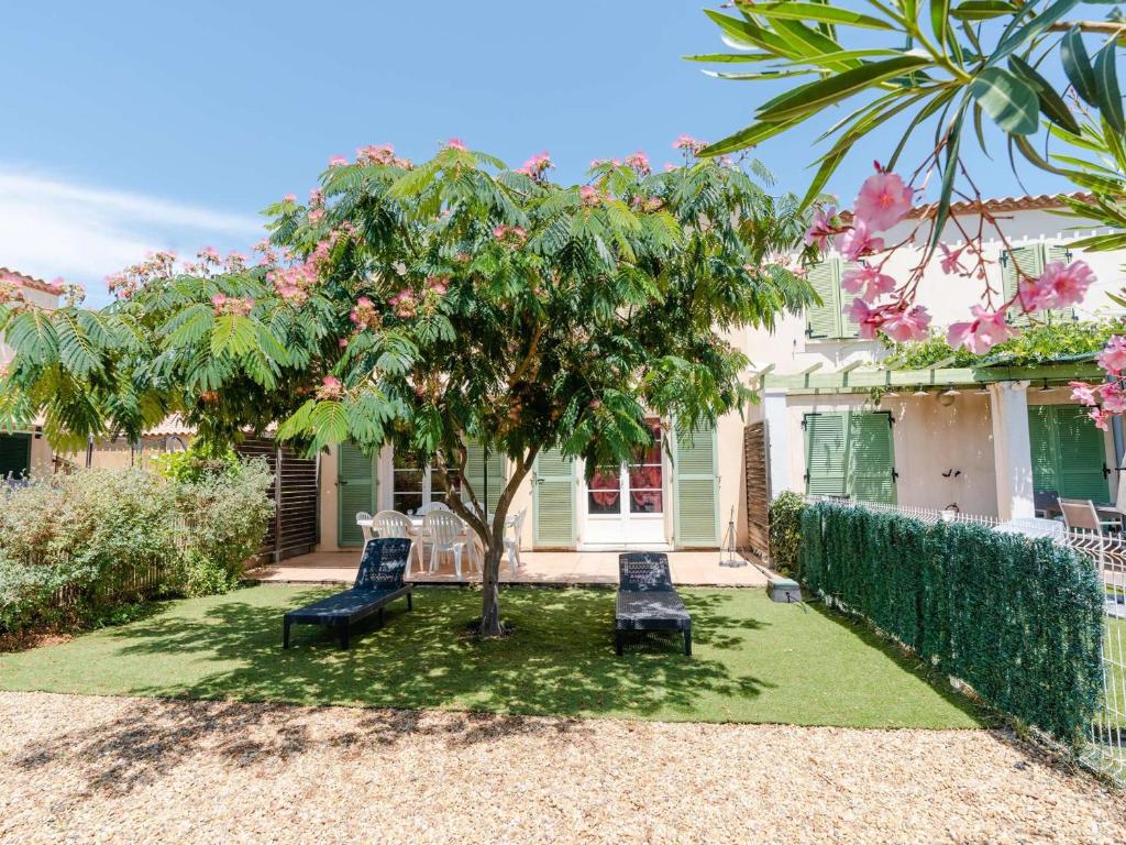 une maison avec deux chaises et un arbre dans la cour dans l'établissement Villa 4 pièces pour 6 personnes avec terrasse, jardin, garage et WIFI à Narbonne-Plage - FR-1-409-136, à Narbonne-Plage