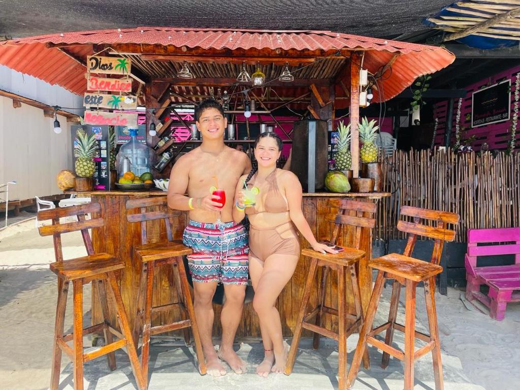 a man and a woman standing in front of a bar at Tours Mandala Beach in Baru