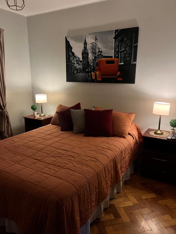 a bedroom with a bed with a orange comforter at Departamento Céntrico San Miguel de Tucuman in San Miguel de Tucumán