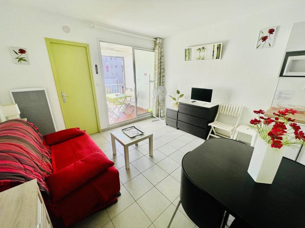 un salon avec un canapé rouge et une table dans l'établissement Studio rénové, 4 pers, parking privé, proche port et plage - Cap d'Agde - FR-1-723-127, au Cap d'Agde