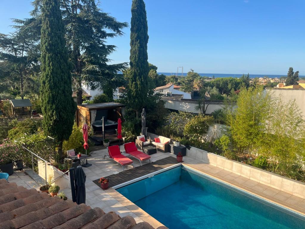 uma piscina num quintal com duas cadeiras vermelhas em VILLA NATURISTE JO&SPA ANNA'BELLA Luxury Suites "naturist couples only" em Cap d'Agde