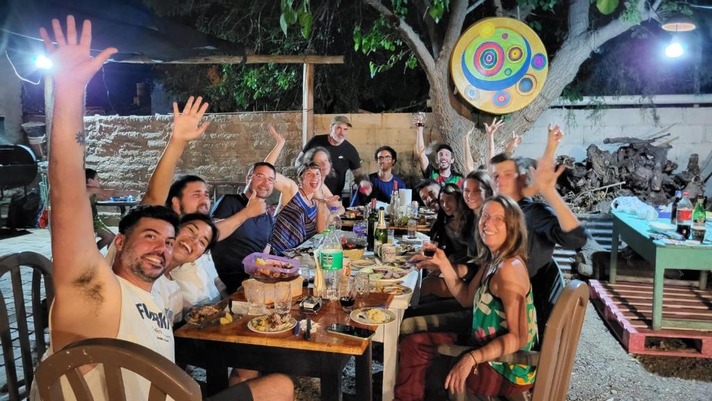 een groep mensen die aan een tafel zitten met hun handen in de lucht bij Huaka Hostal in Cafayate