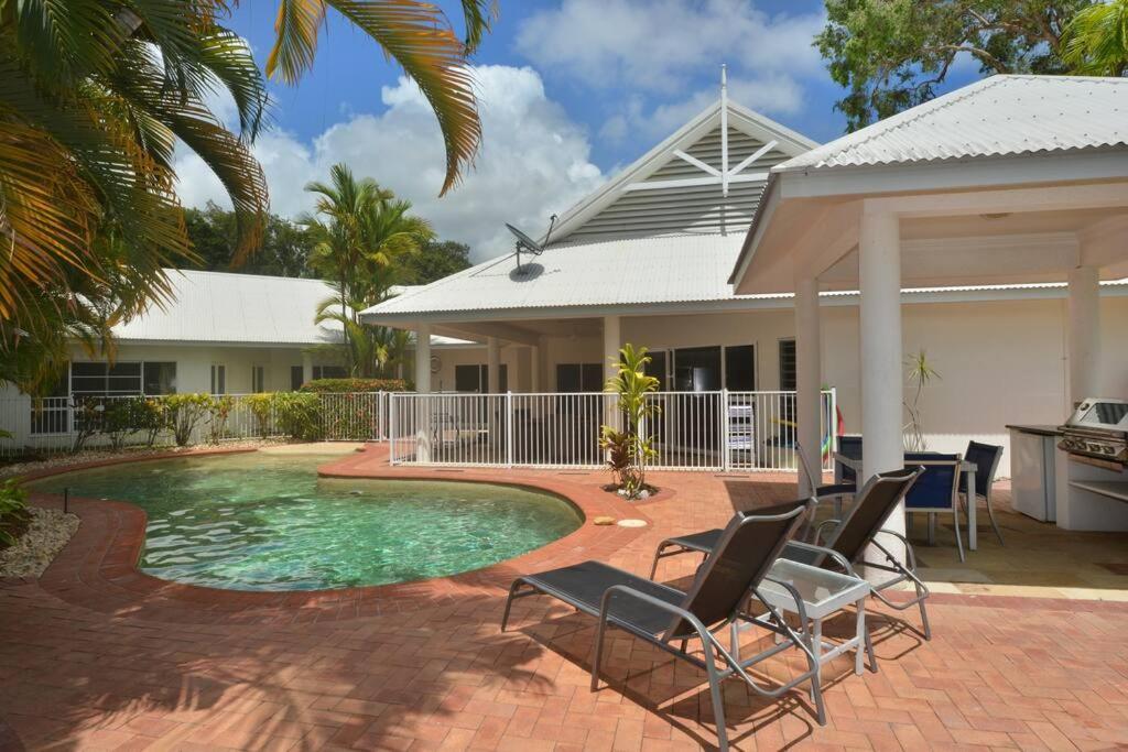 ein Haus mit Pool und Stühlen davor in der Unterkunft Solander House - 5 Bedrooms by the Beach in Port Douglas