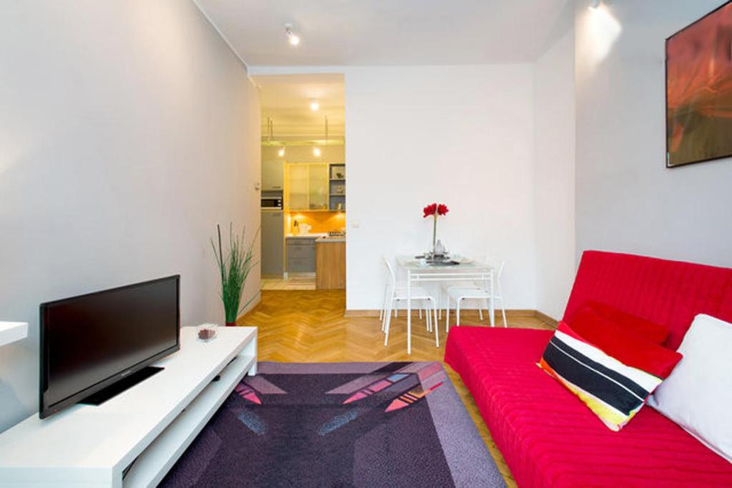 ein Wohnzimmer mit einem roten Sofa und einem TV in der Unterkunft Apartament Amaryllis in Krakau