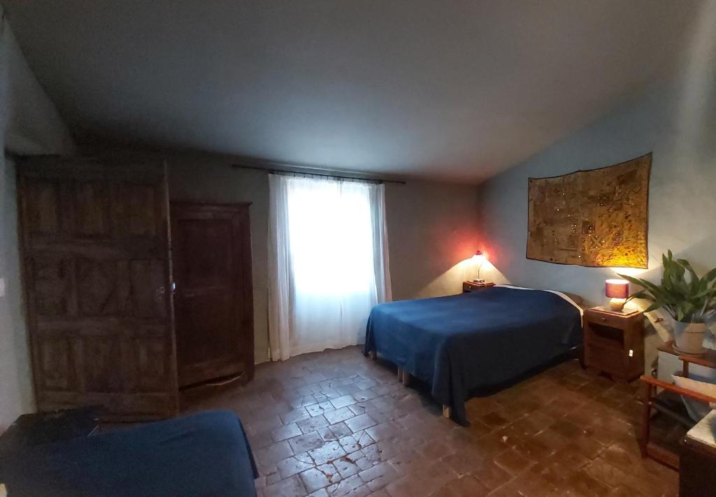 a bedroom with a blue bed and a window at Maison d'Almes in Adissan