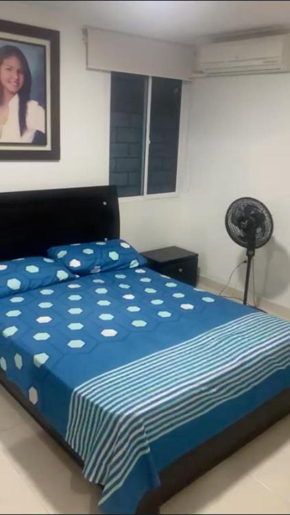 a bed with a blue comforter in a bedroom at Habitacion en casa familiar in Barranquilla