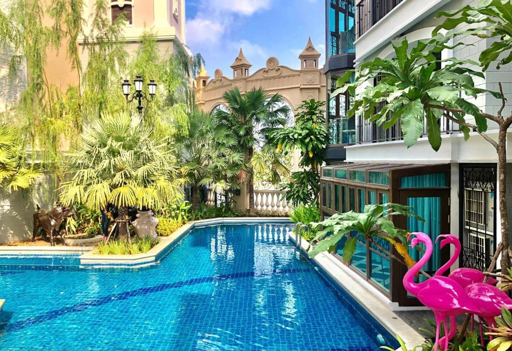a swimming pool in front of a building with a pink flamingo at Espana Resort Jomtien Beach Pattaya in Jomtien Beach