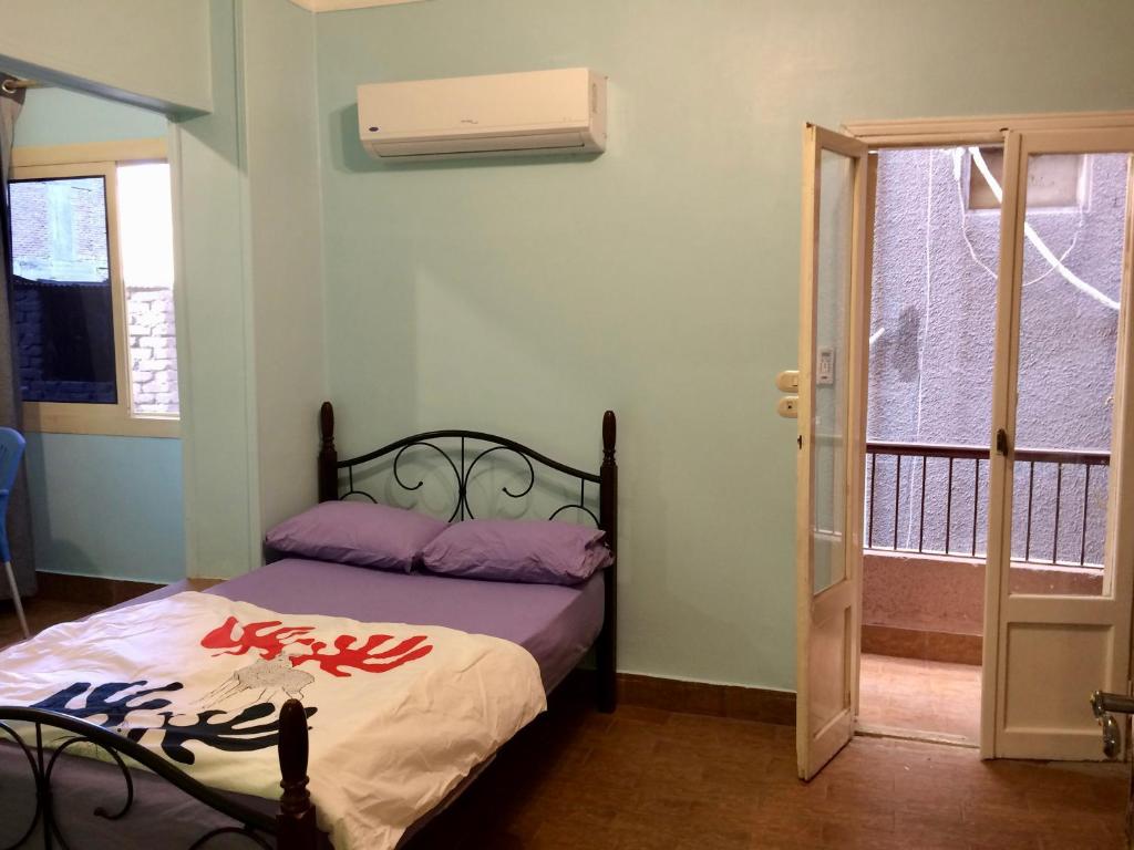 een slaapkamer met een bed met paarse lakens en een raam bij Men’s Retreat: Cozy Room with Free WiFi & AC in Caïro