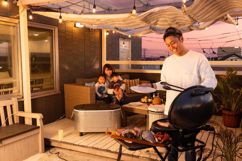 a man cooking on a patio with a woman and a child at パプリカホテルです in Kisarazu