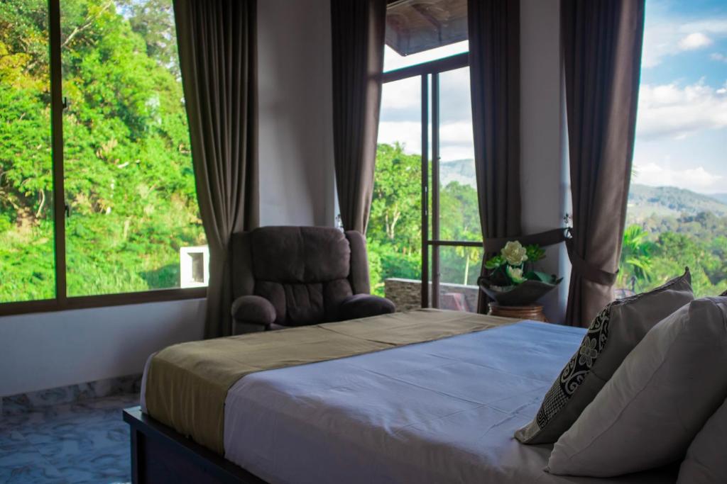 um quarto com uma cama, uma cadeira e janelas em Boscage Homestay em Kandy