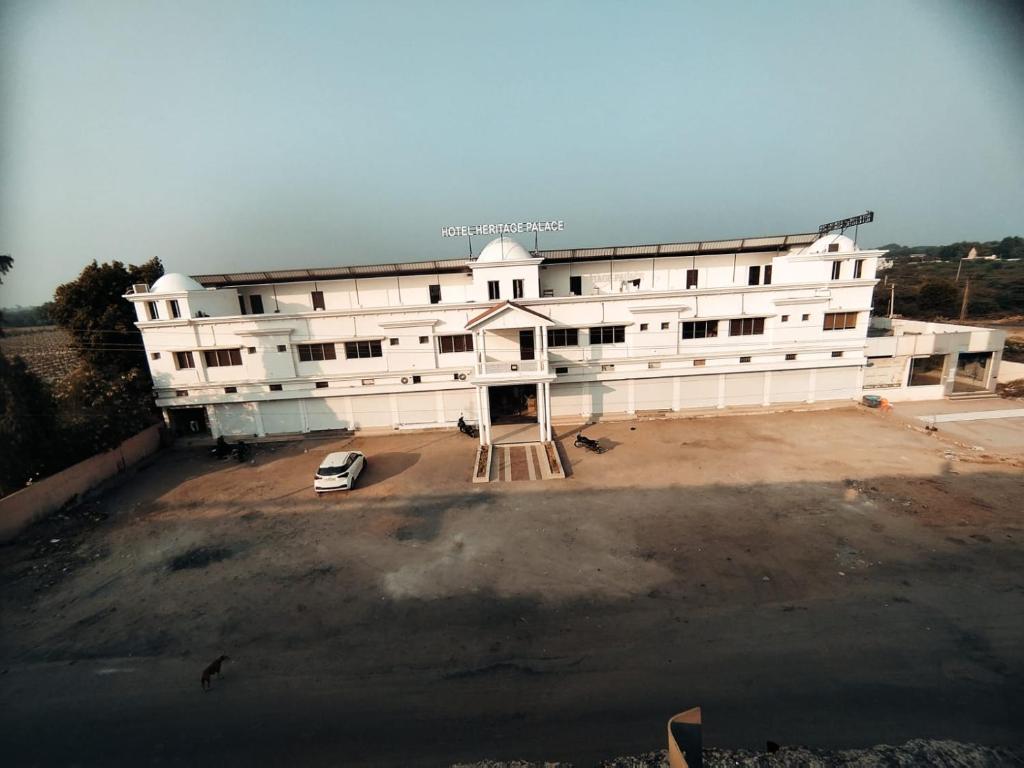 een groot wit gebouw met een auto voor de deur bij Hotel Heritage Palace in Bhuj