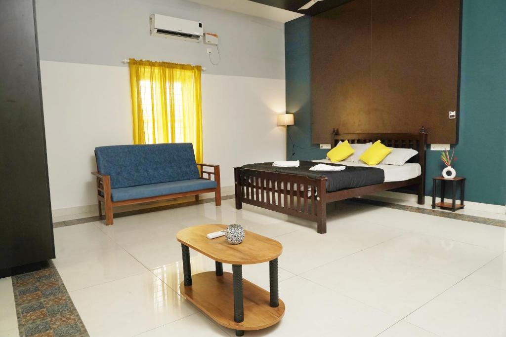 1 dormitorio con cama, sofá y mesa en ORANGE VALLEY TOWN RESIDENCY, en Trivandrum