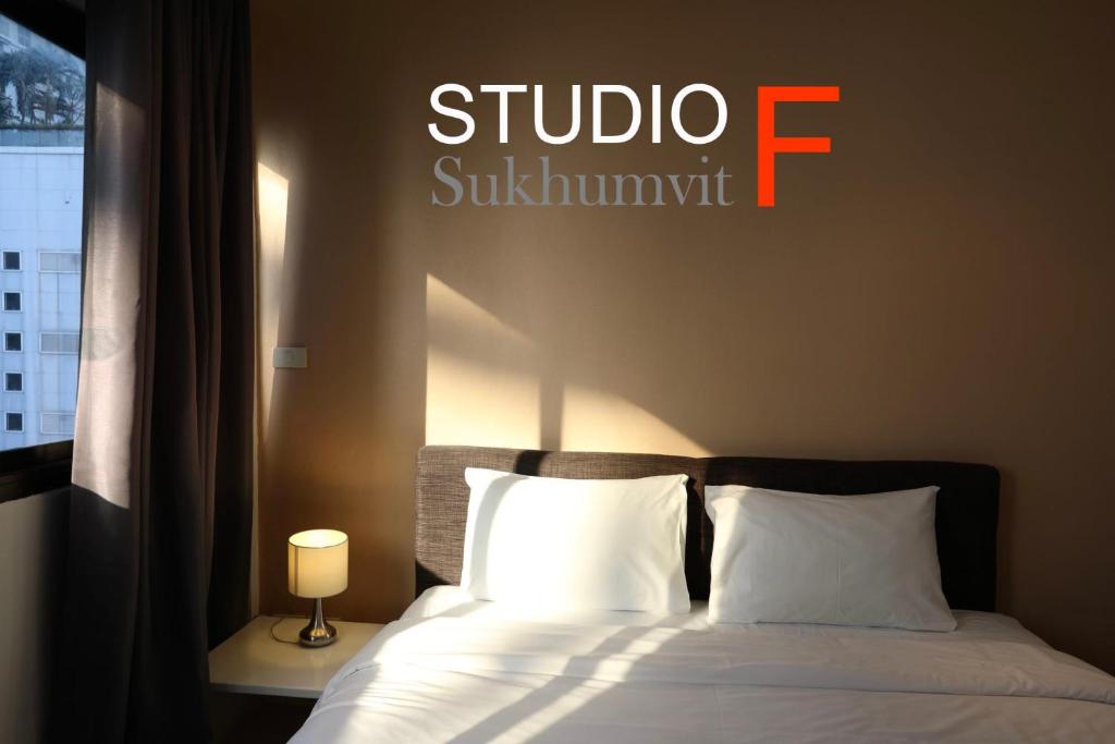a bedroom with a bed with a sign on the wall at Studio F Sukhumvit in Bangkok