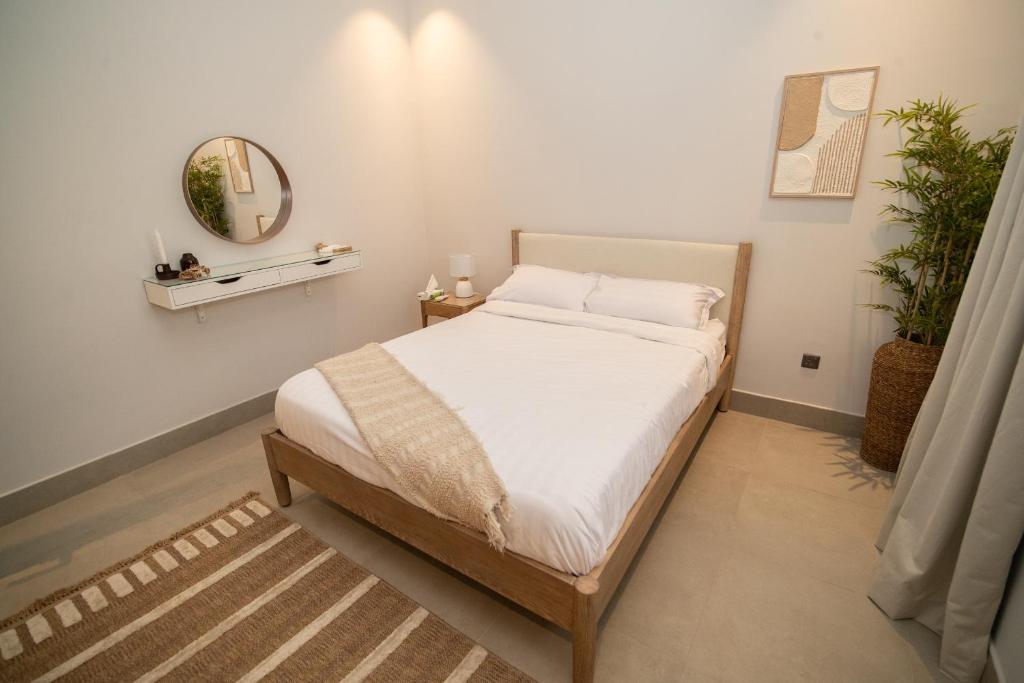 Schlafzimmer mit einem Bett mit weißer Bettwäsche und einem Spiegel in der Unterkunft SAQEEFA 9 - A01 - Self Entrance in Riad