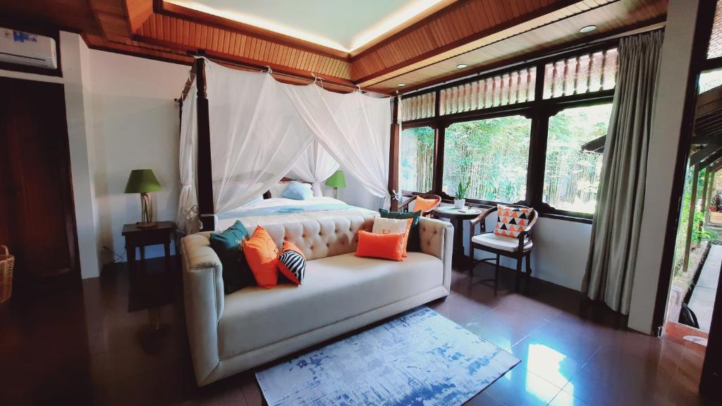 a bedroom with a white couch in a room with windows at Villia magnolia sanur bali 巴厘島玉蘭別墅 in Denpasar