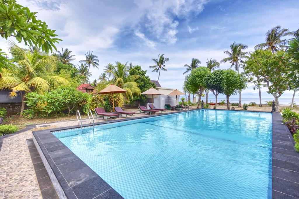 a swimming pool at a resort with palm trees at Putri Nusa Beach in Nusa Penida