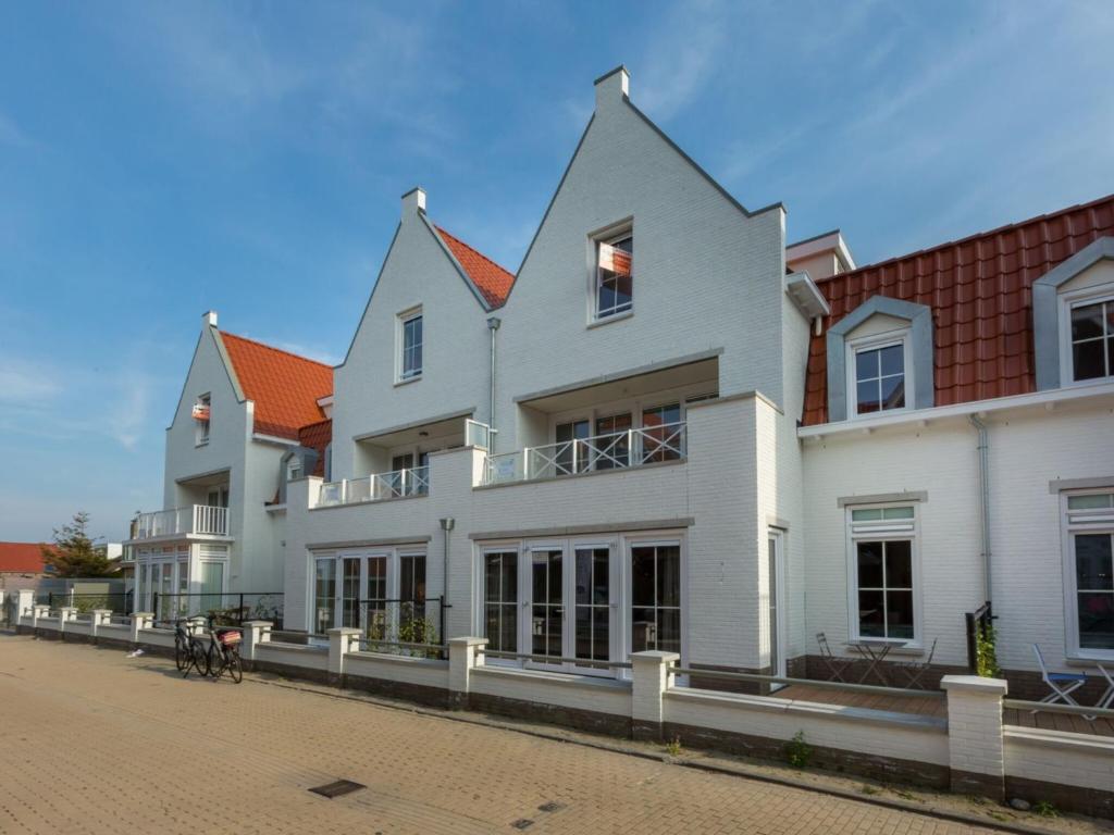 un gran edificio blanco al lado de una calle en Luxury apartment with Sauna the foot of the dunes, en Koudekerke