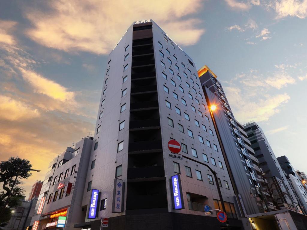 a tall white building with blue signs on it at Dormy Inn Ueno Okachimachi in Tokyo