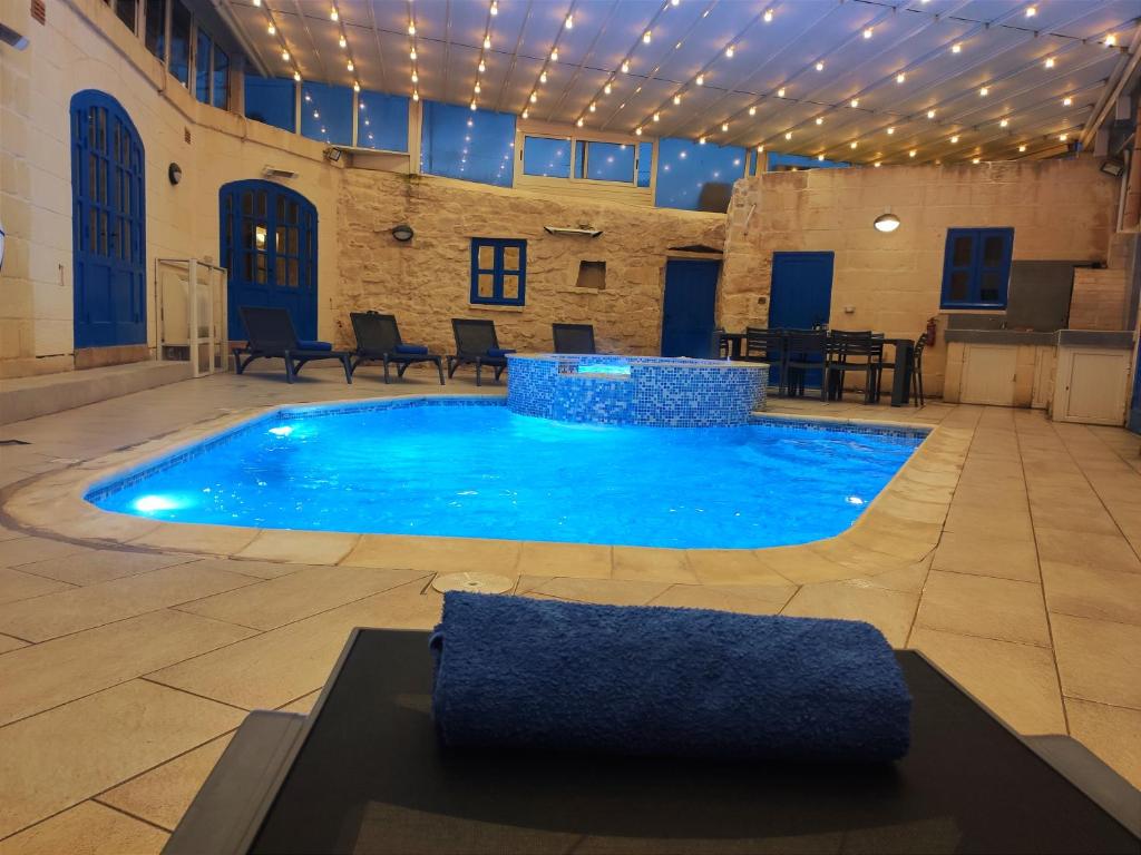 a large pool in a building with a table and chairs at Margerita Farmhouse in Qrendi