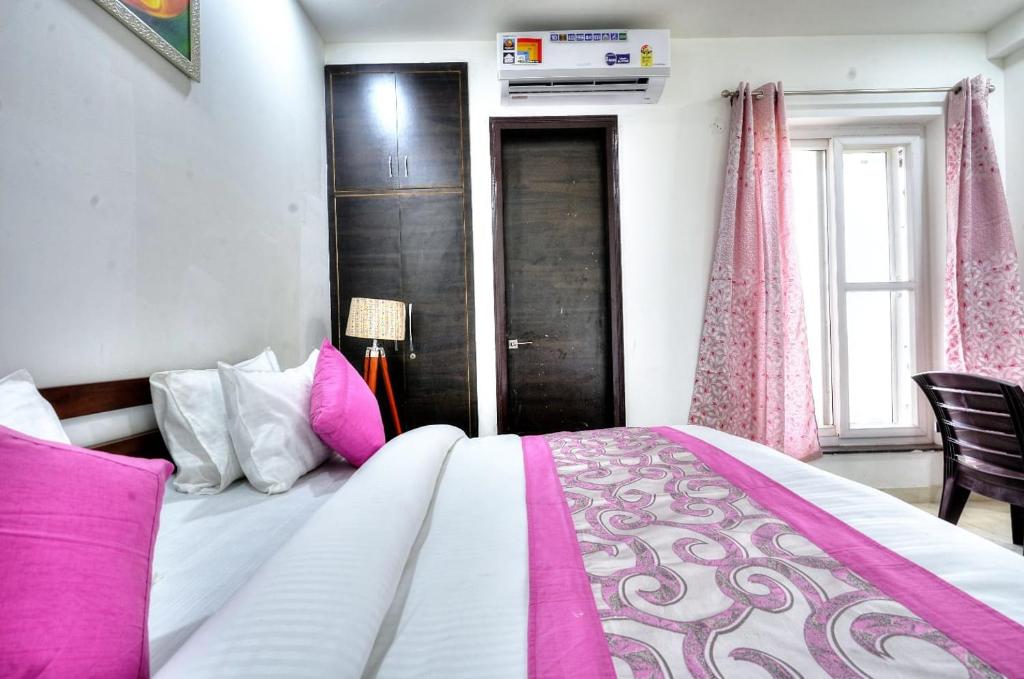 una camera da letto con un grande letto con cuscini rosa e bianchi di The Noble Suites, Near Spectrum Mall a Noida