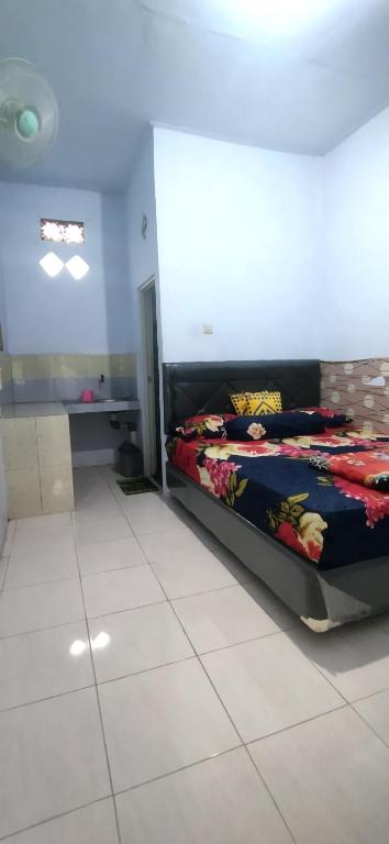 a bedroom with a bed and a white tile floor at Umah isun guests house in Banyuwangi