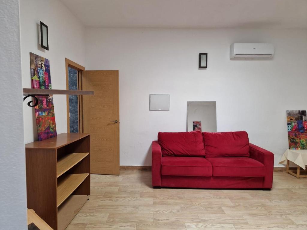 sala de estar con sofá rojo y mesa en Cortijo barranco higuera 2 en Fernán Pérez