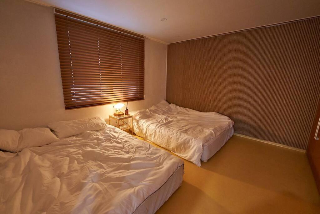 two twin beds in a room with a window at Mapo Villa in Shinchon in Seoul