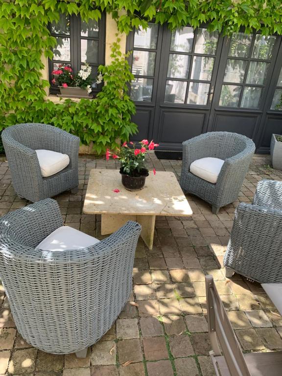 d'une terrasse avec des chaises en osier et une table fleurie. dans l'établissement Gite MCM, à Chalais