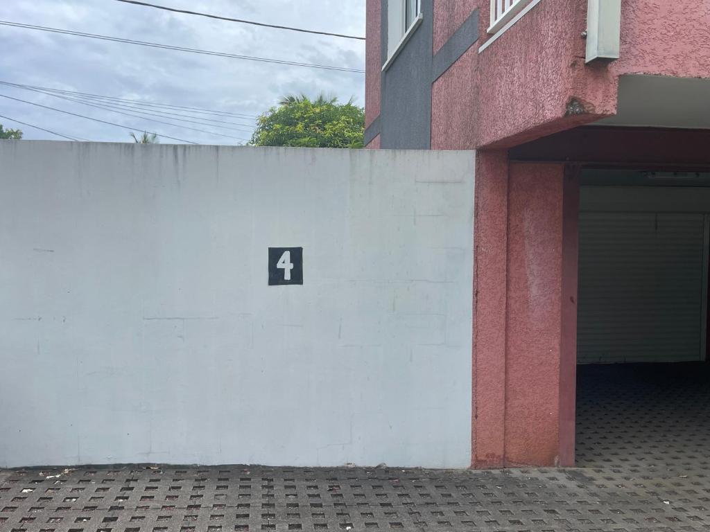 a white wall with a number four on it next to a building at CASA COLIVING avec chambre salle de bain individuelles privatives in Saint-Pierre