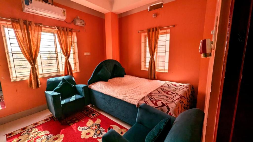 Schlafzimmer mit orangefarbenen Wänden, einem Bett und einem Stuhl in der Unterkunft Veda Homestay in Agartala