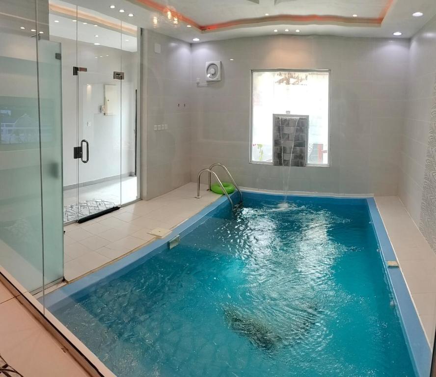 a bathroom with a large swimming pool with a shower at فلل الكناري الراقية in Taif