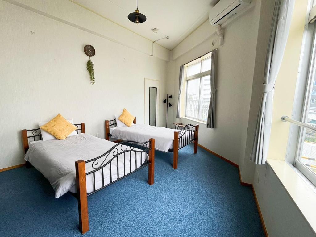 Guest House Umikaji في ناها: سريرين في غرفة بها نافذتين