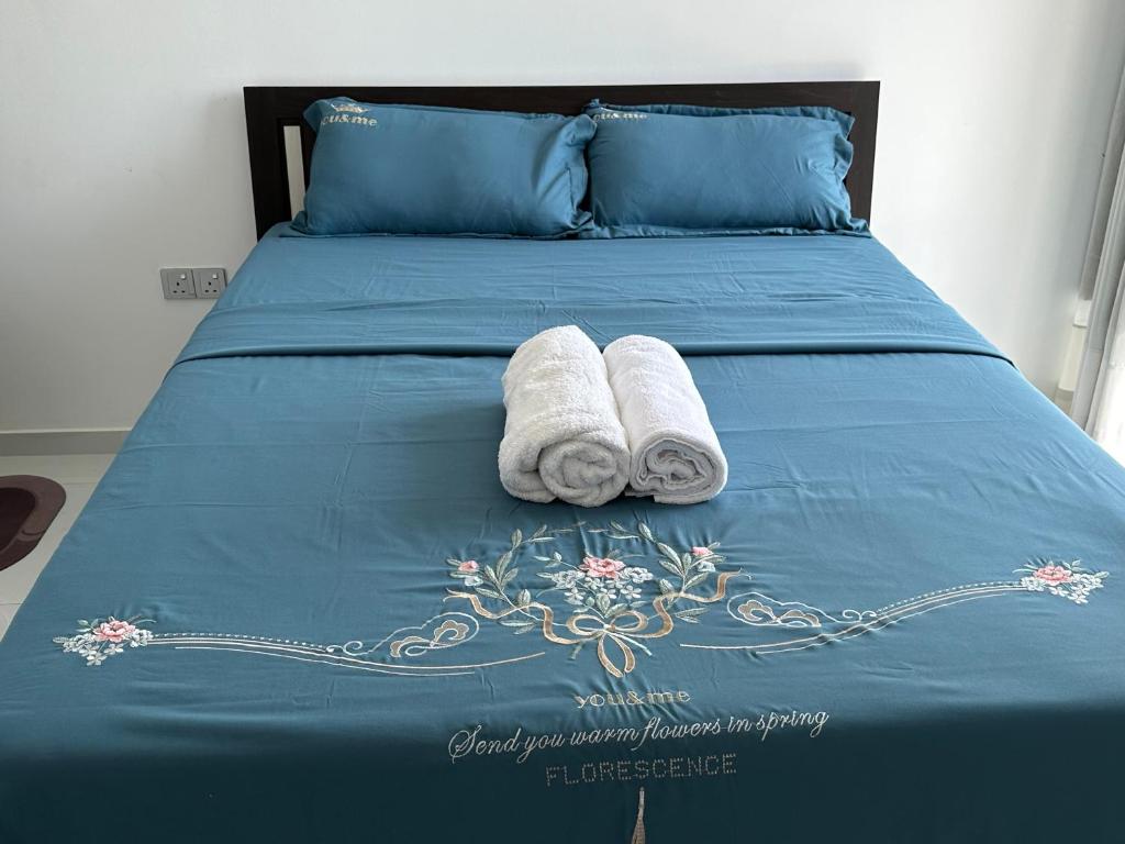 zwei Rollen Handtücher auf einem Bett mit blauer Bettwäsche in der Unterkunft Beach road 3 bedroom in Karagampitiya