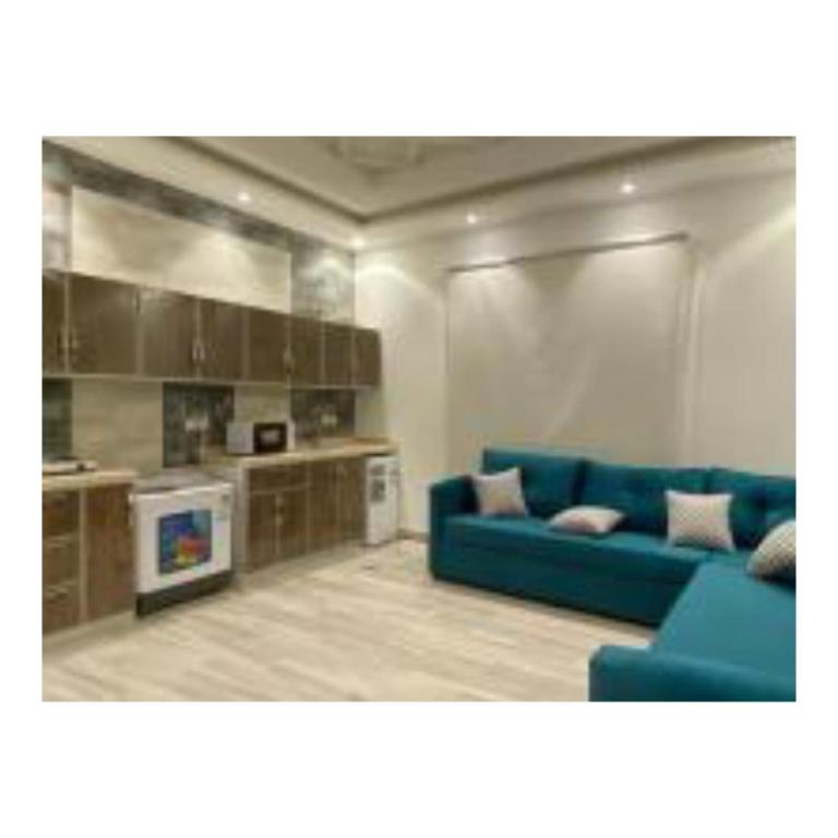 a living room with a blue couch and a kitchen at Diamond suites in Al Madinah
