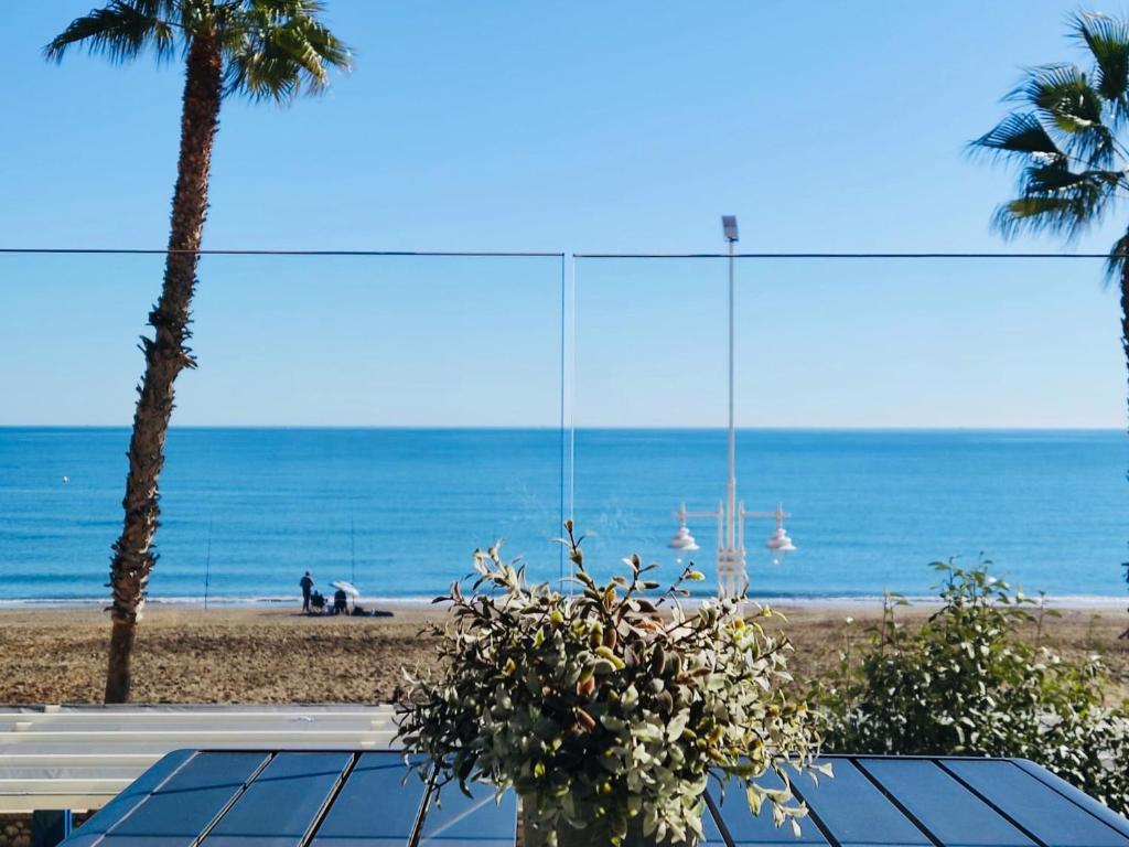Blick auf das Meer von einem Strand mit Palmen in der Unterkunft Gran vivienda de lujo frente al mar in Málaga