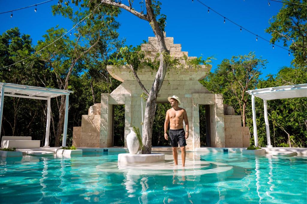 a man standing in the water in a pool at The Yellow Nest Tulum in Tulum