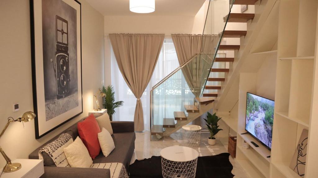 un soggiorno con divano e una scala di Desert Rose Apartment- Masdar City a Al Qurayyah