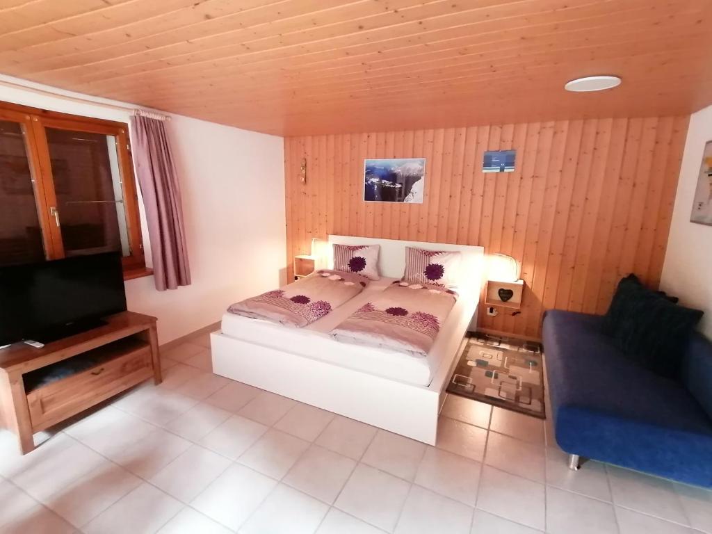 1 dormitorio con 1 cama, TV y sofá en FEWO Rophaienblick, en Isenthal