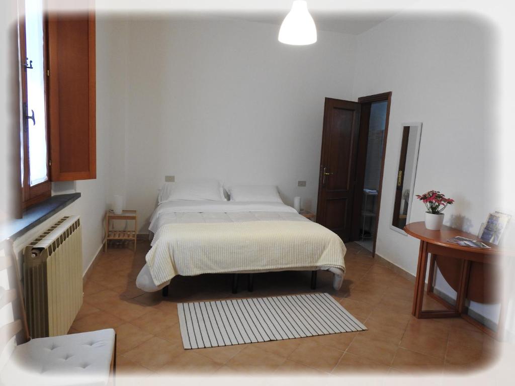 Dormitorio blanco con cama y mesa en Geoglobe Apartment, en Pisa