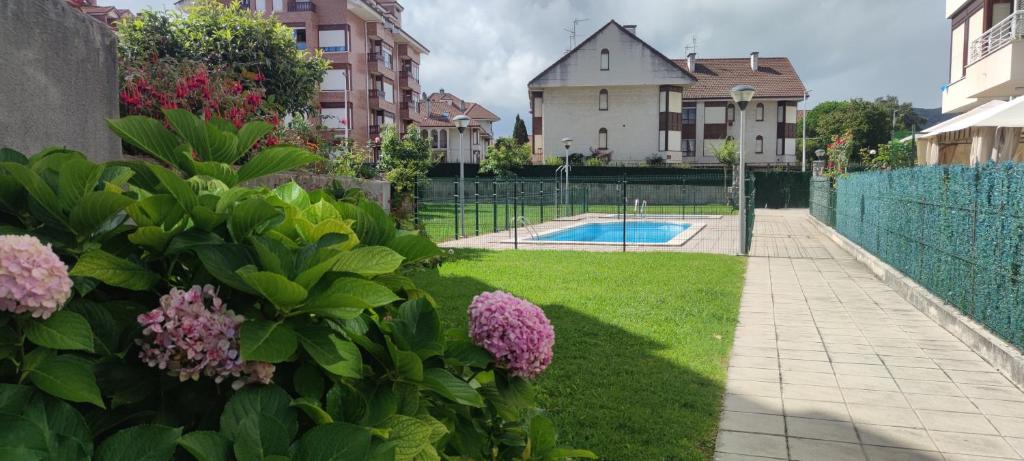 un jardín con flores y una piscina en Apartamento Turístico Los Altos en Noja