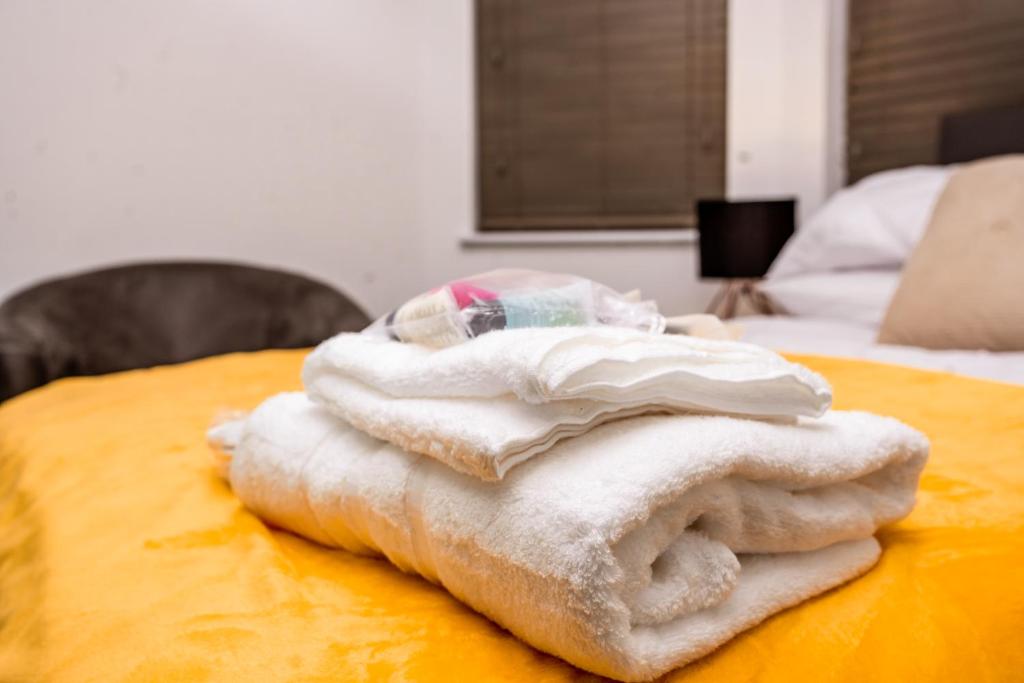 a pile of towels sitting on top of a bed at Divine Stay in Coventry