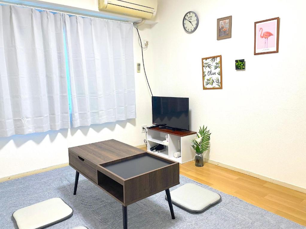 a living room with a coffee table and a tv at FUKUOKA airport line Ijiri st self check in apartment in Fukuoka