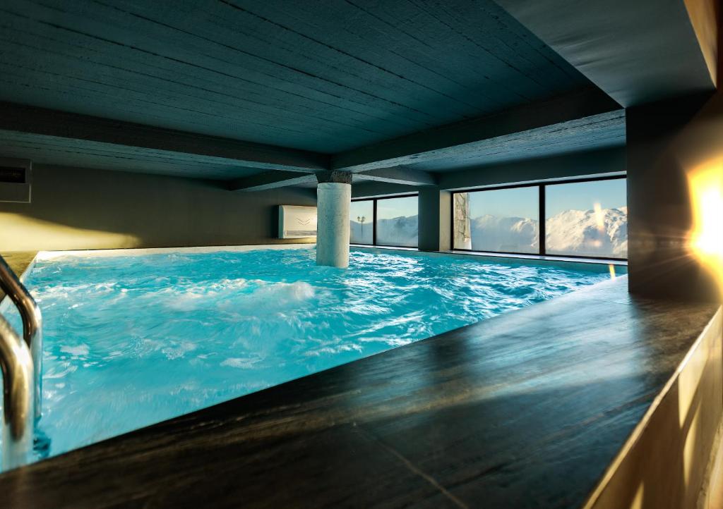 a large swimming pool with blue water in a room at Hotel Carpe Diem Gudauri in Gudauri