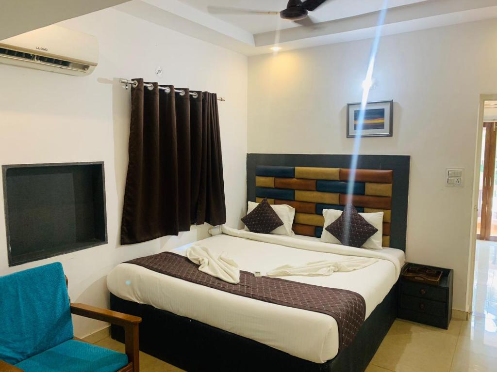 a bedroom with a bed and a chair and a television at 1 Bhk Apartment 200 mtr from beach in Calangute