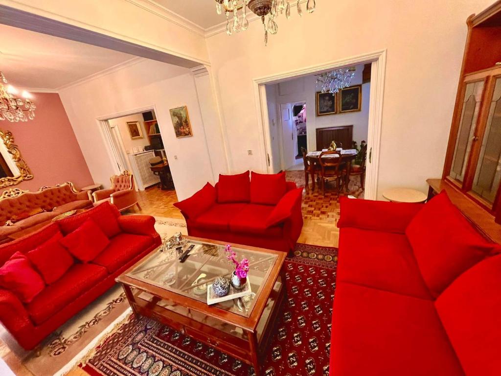 アテネにある100 m2 Apartment in the center of Athensのリビングルーム(赤いソファ、テーブル付)