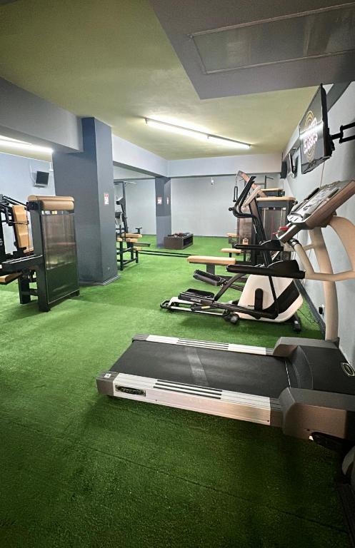 a gym with green carpeted floors and a room with machines at Thalia deco City & Beach Hotel in Hersonissos