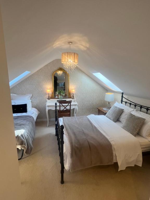 a bedroom with two beds and a mirror at Highcroft House in Corsham
