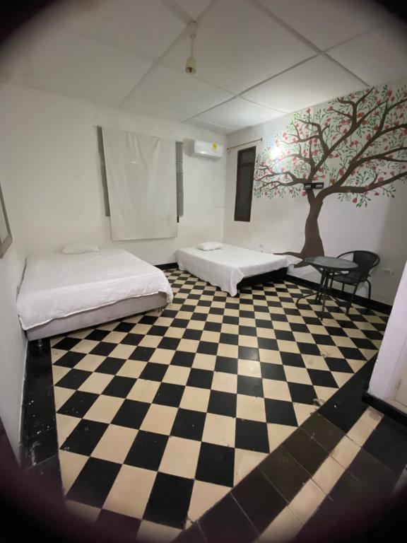 ein Zimmer mit 2 Betten und einem Baum auf einem karierten Boden in der Unterkunft VEGAN GARDEN HOSTAL in Barranquilla