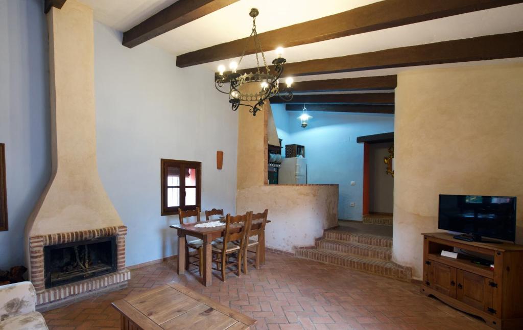 a living room with a fireplace and a table and a tv at Paraje del Hueznar in Cazalla de la Sierra